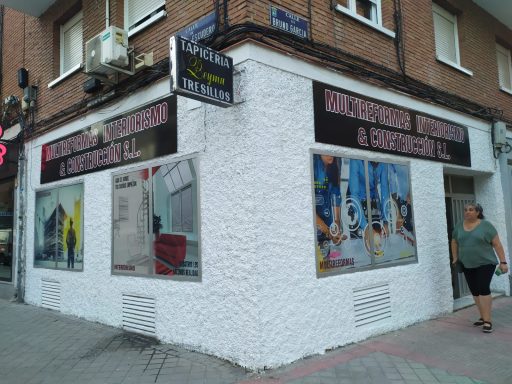 Fachada de una tienda con carteles y una mujer caminando por la acera.